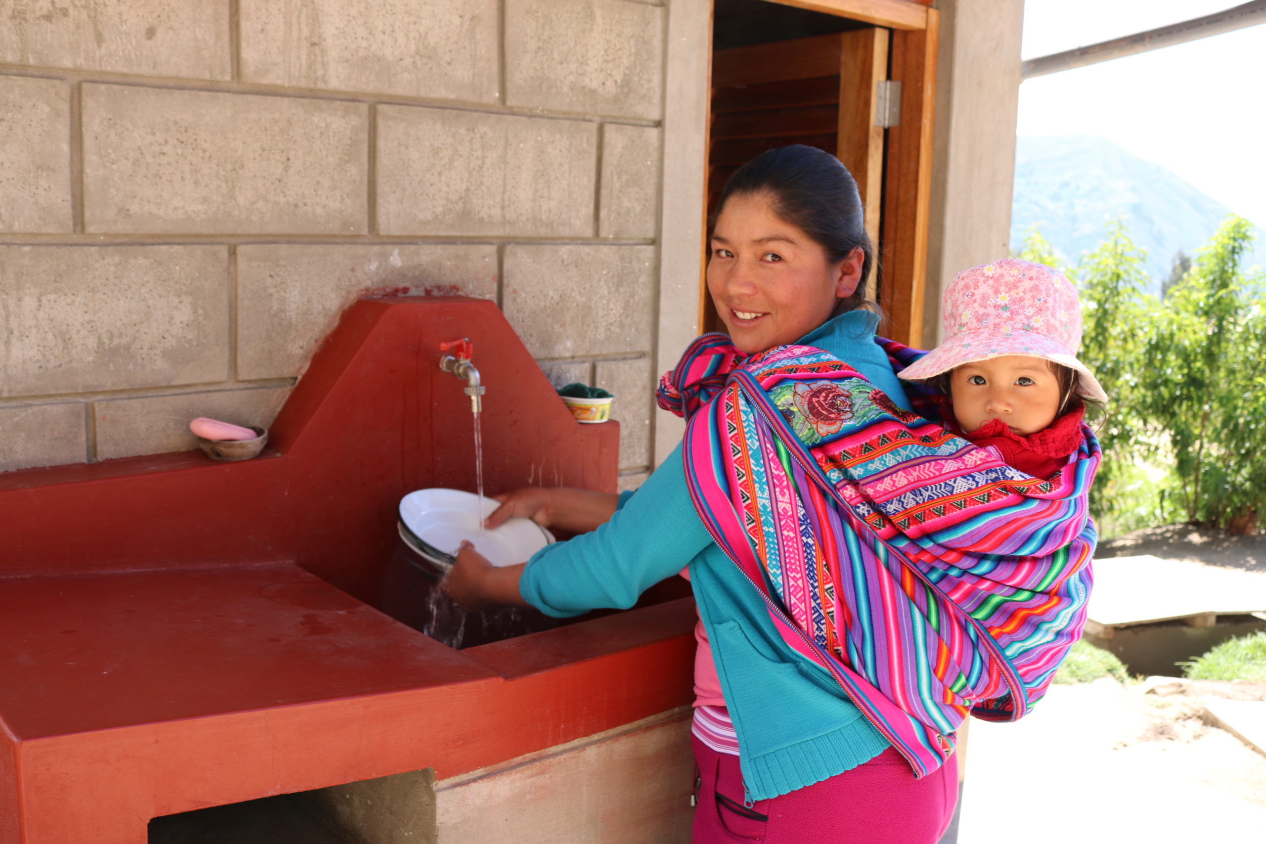 Mujer lavando los platos con su hijo Perú